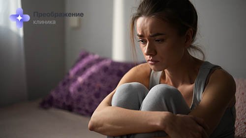 Девушка грустит, обнимая свои колени